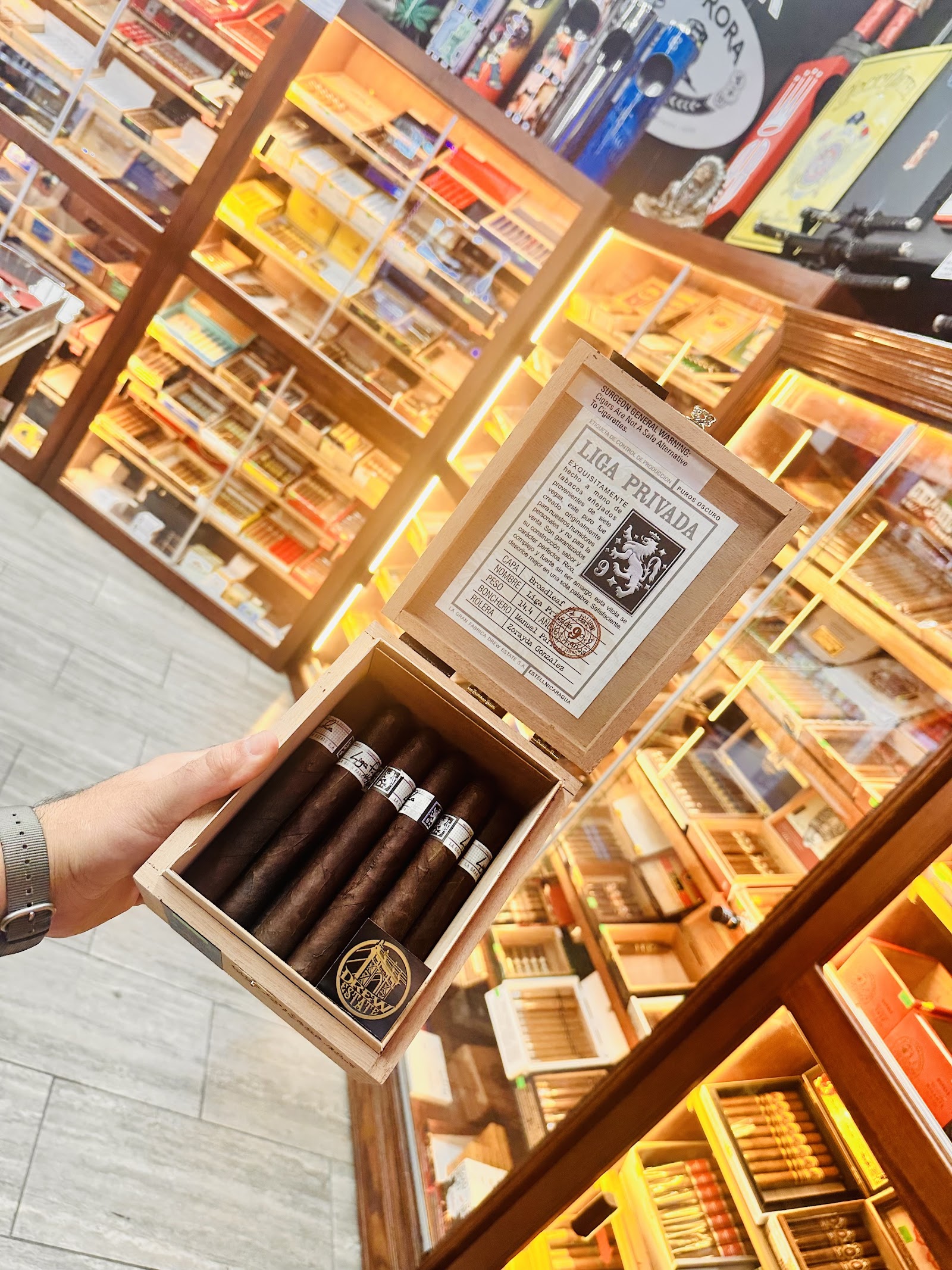 An open box of Liga Privada cigars with dark Connecticut Broadleaf wrappers and ornate cream band art.