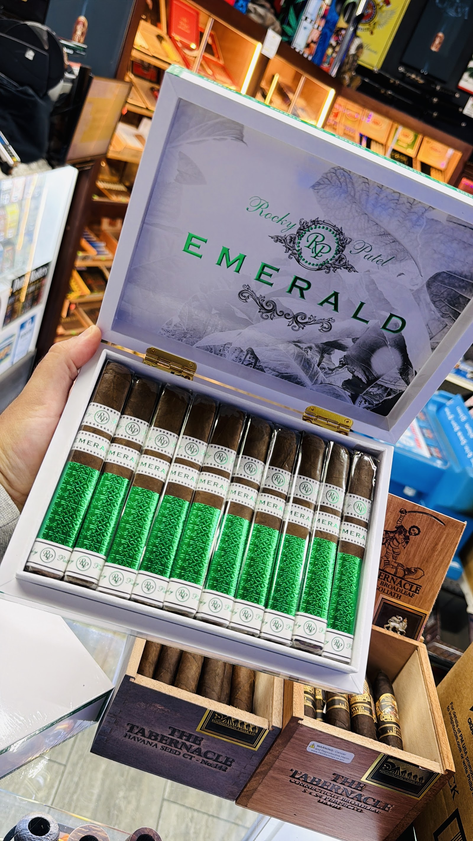 A box of Rocky Patel Emerald cigars with bright green foot-bands.